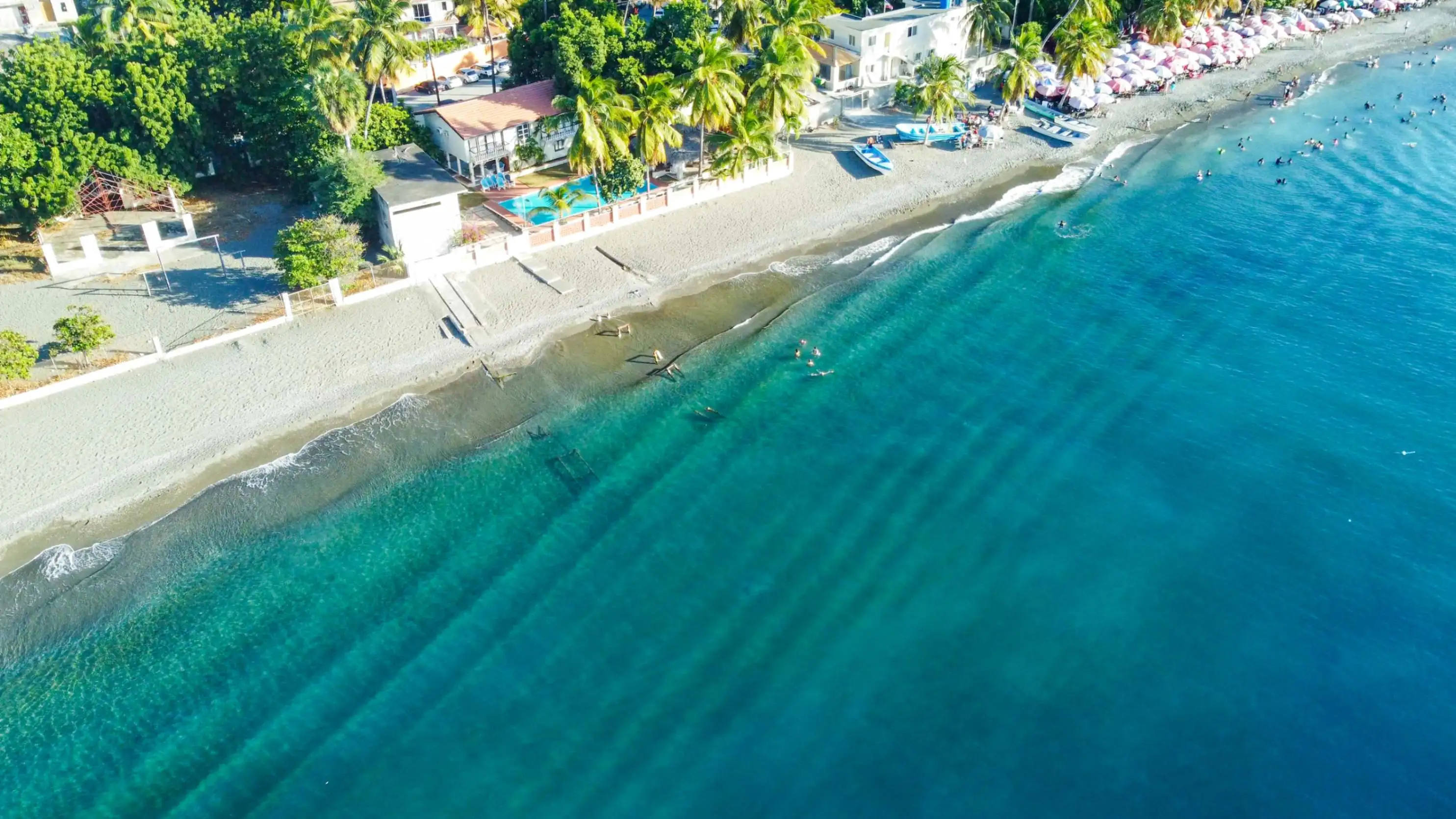 Detalle de la orilla de Playa Palmar de Ocoa con arena negra y agua clara